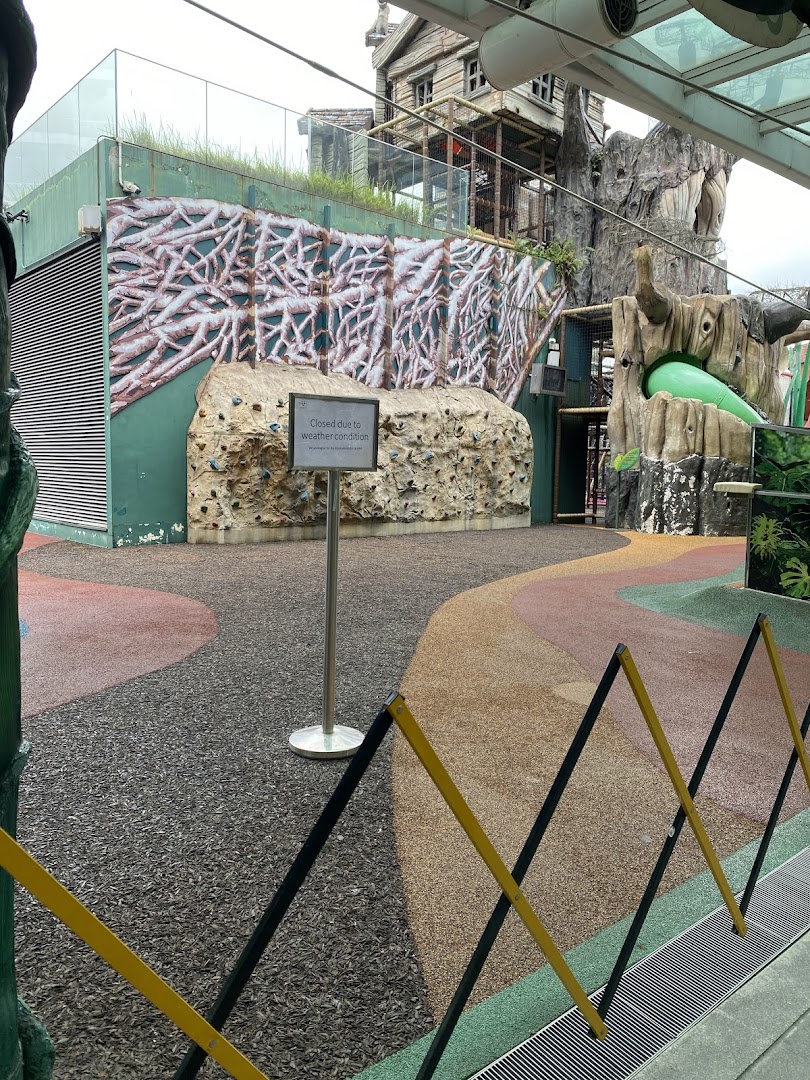 An outdoor adventure play area with climbing walls and treehouse structures, currently closed due to weather conditions.