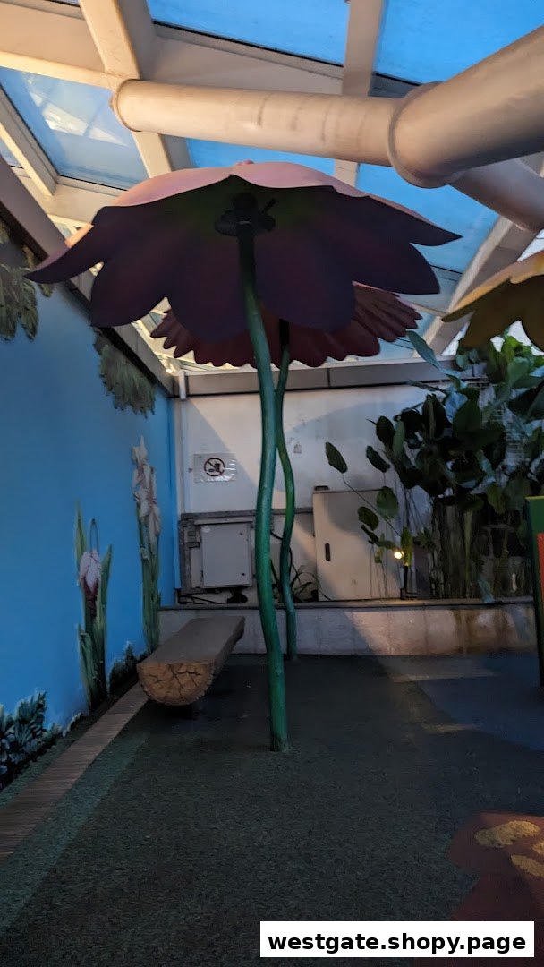 A whimsical indoor play area featuring oversized flower decorations, a log bench, and painted nature scenes.