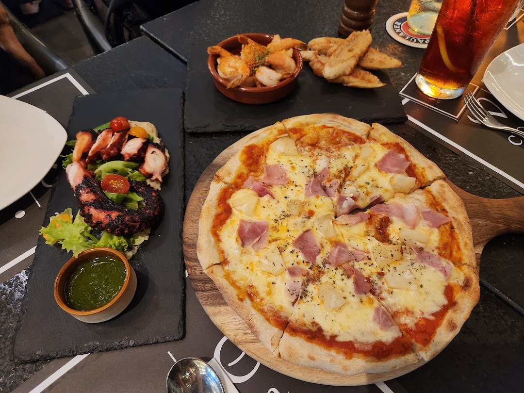 A table laden with a delicious pizza, grilled octopus salad, and various appetizers at Wine Connection Bistro.
