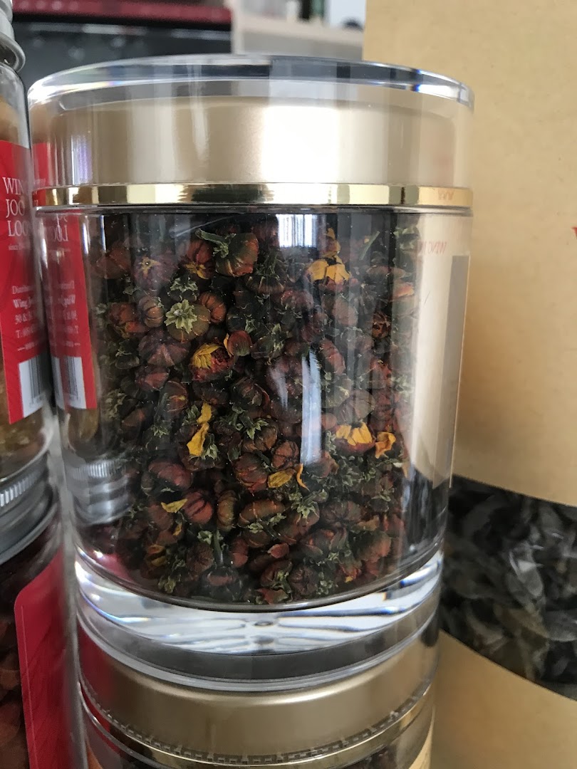 A clear jar filled with dried flower buds, likely for tea or herbal remedies, displayed in a shop.