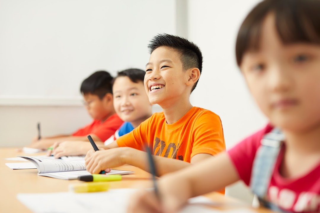 Happy children actively learning and writing in a bright classroom setting.