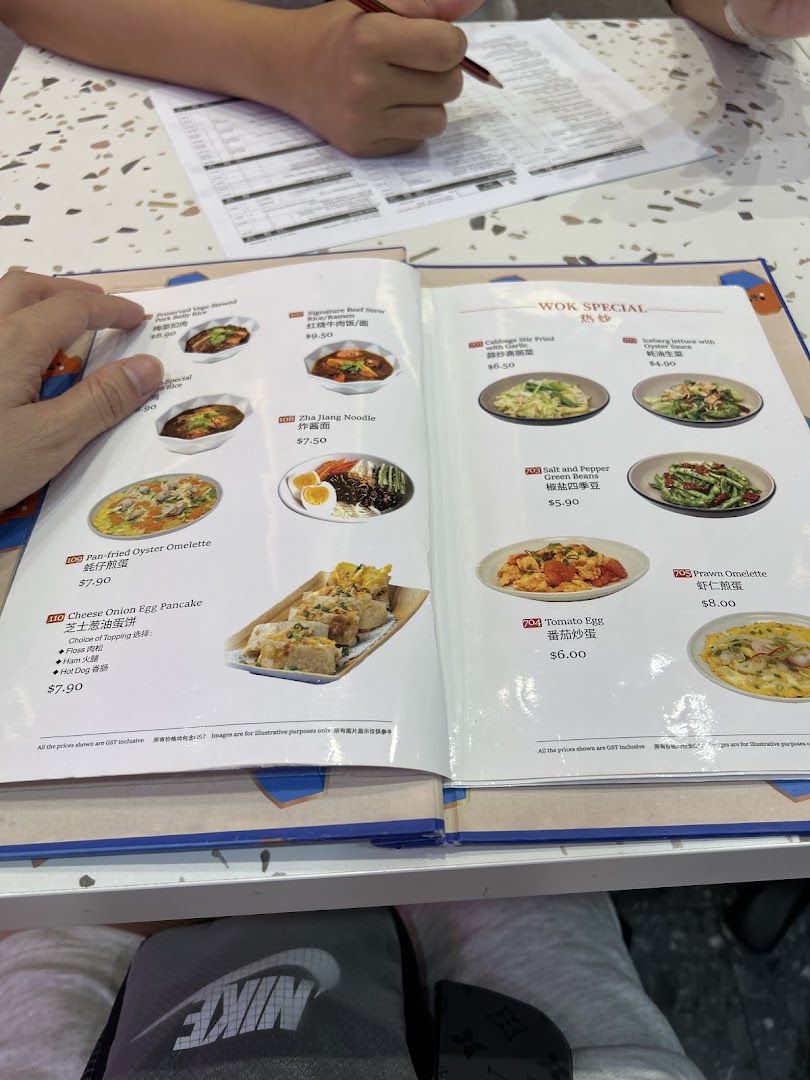 A customer's hands holding an open menu displaying various Taiwanese dishes and their prices.