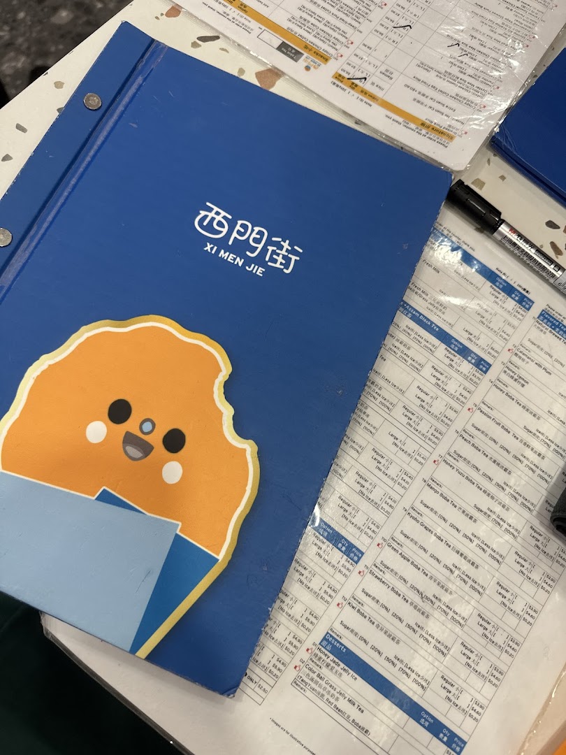 A blue menu booklet for Xi Men Jie and laminated menu sheets displaying various Taiwanese drinks and desserts.