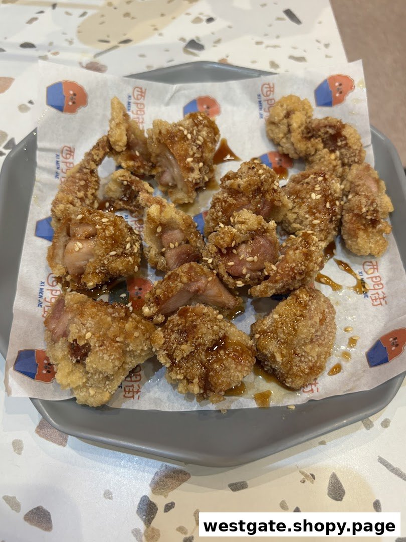 A close-up of crispy, golden-brown fried chicken pieces with sesame seeds and sauce on a plate.