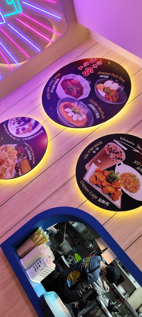 Illuminated circular displays showcasing popular Taiwanese dishes and drinks, with a glimpse of the kitchen.