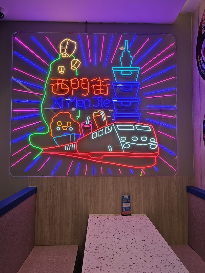 A vibrant neon sign featuring Taiwanese landmarks and a train illuminates a cozy dining booth.