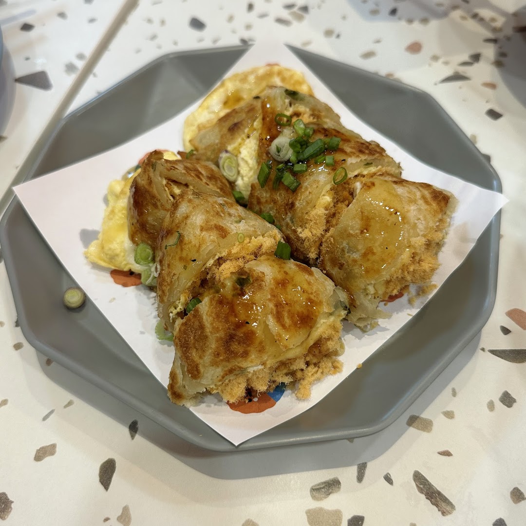 A close-up of a delicious Taiwanese egg pancake (dan bing) with pork floss and a savory sauce.