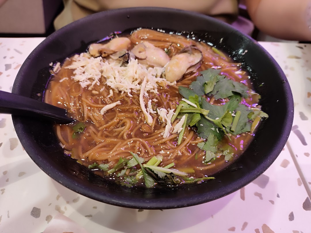 A close-up of a delicious bowl of Taiwanese oyster vermicelli with shredded toppings and fresh herbs.
