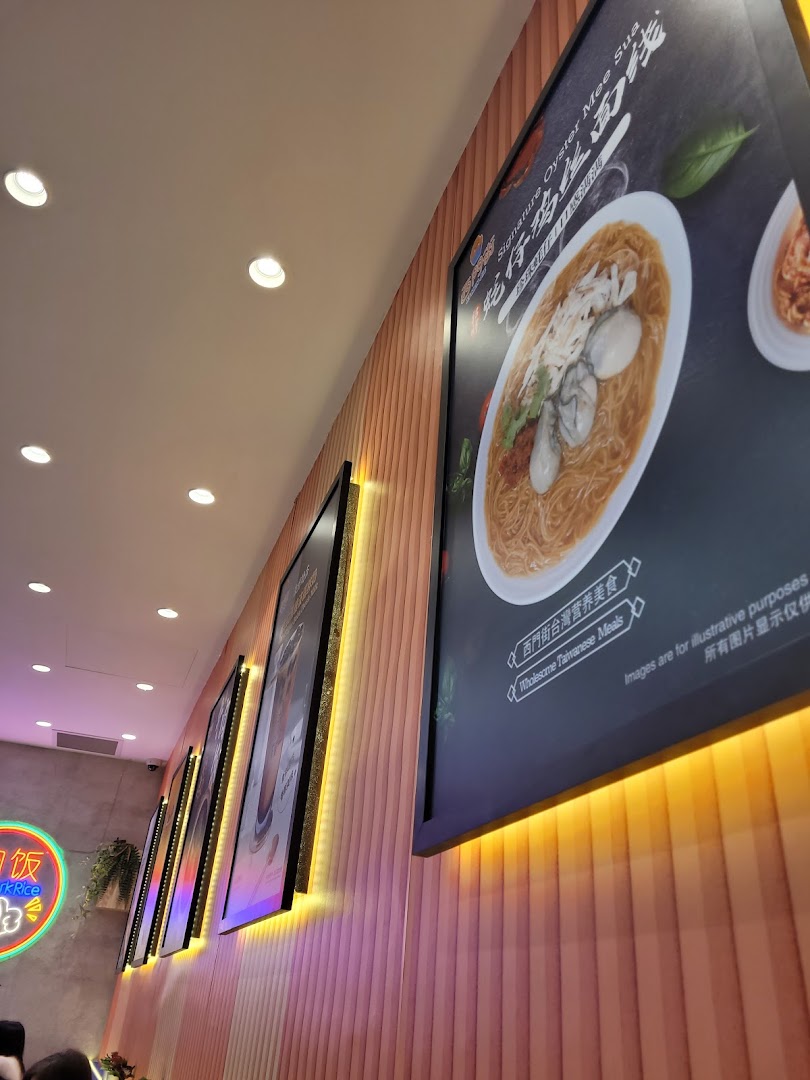 An interior shot of a Taiwanese restaurant featuring large, illuminated posters of signature dishes on a wooden wall.