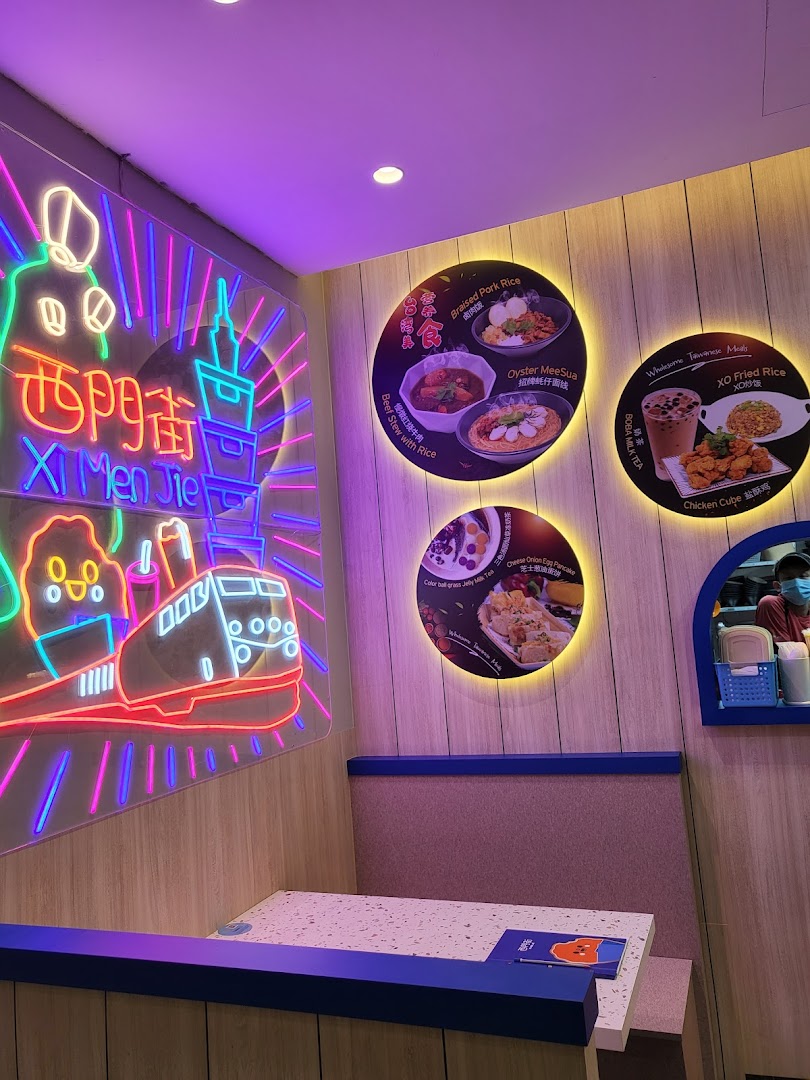 An inviting interior shot of Xi Men Jie, featuring a vibrant neon sign and illuminated food display boards.