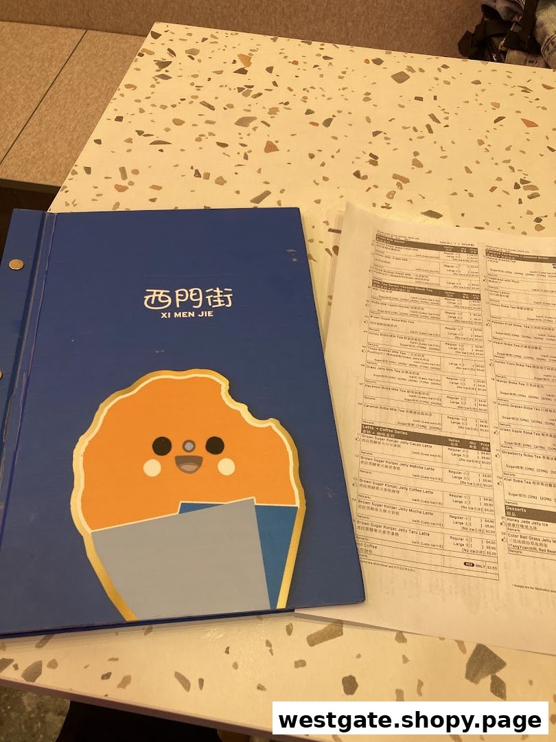A blue menu book and a printed menu sheet for Xi Men Jie on a speckled table.