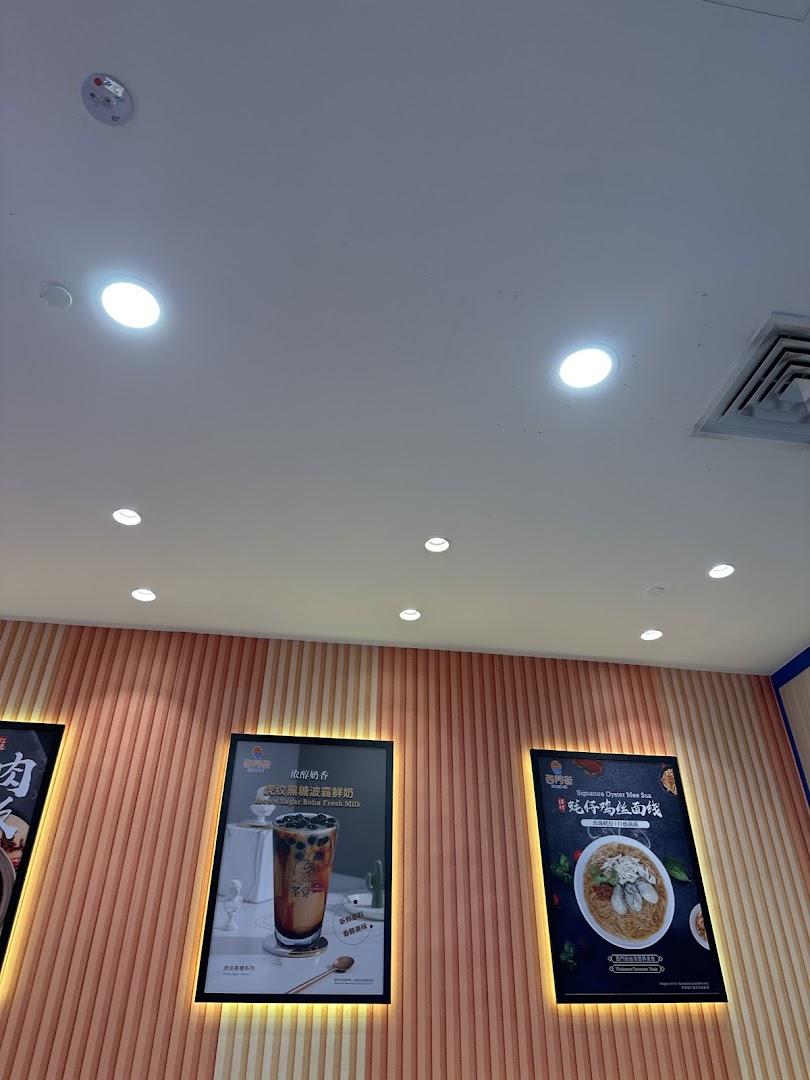 Promotional posters on a textured wall inside Xi Men Jie, featuring a brown sugar boba drink and oyster mee sua.