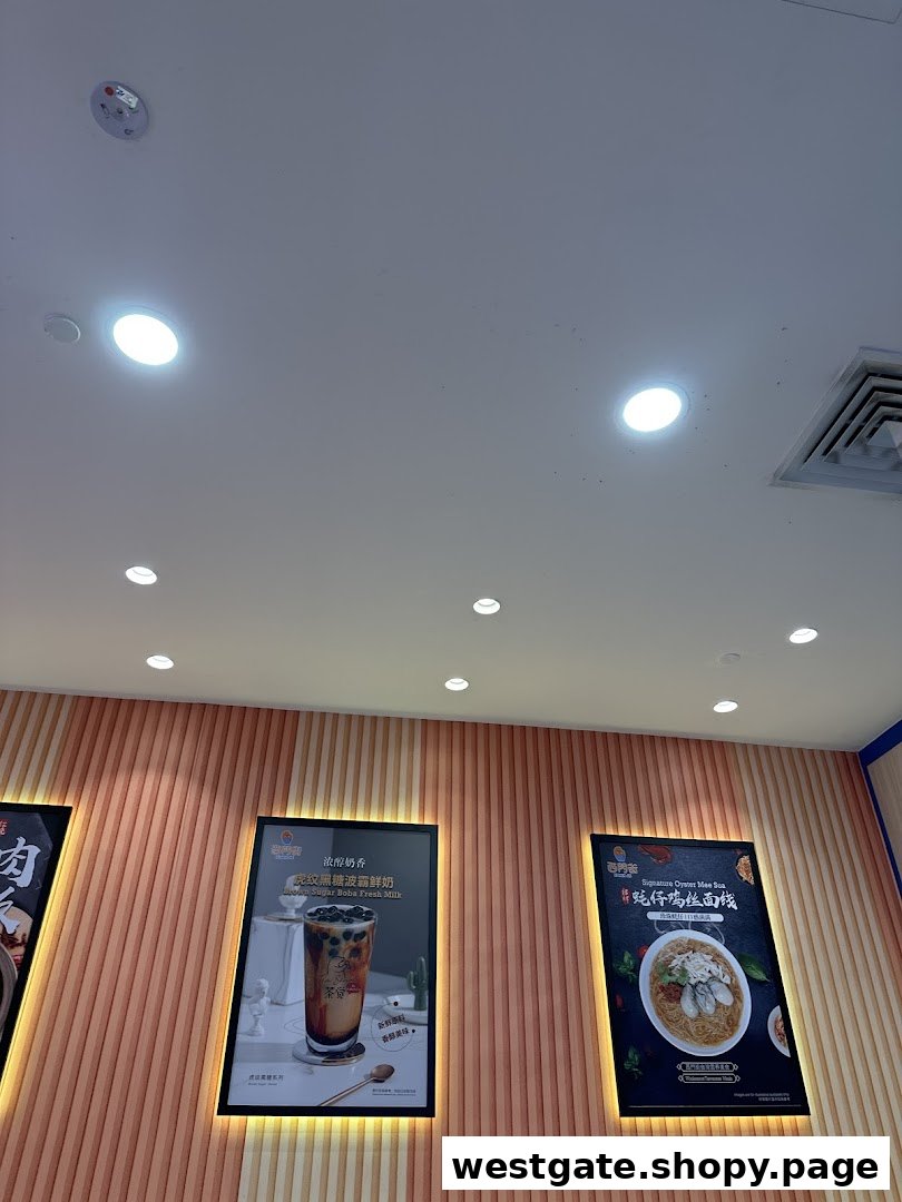 Promotional posters on a textured wall inside Xi Men Jie, featuring a brown sugar boba drink and oyster mee sua.
