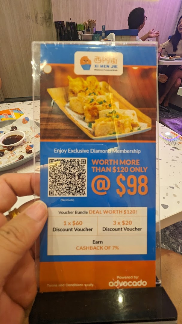 A hand holds a promotional standee for Xi Men Jie's Diamond Membership, featuring a food image and membership benefits.