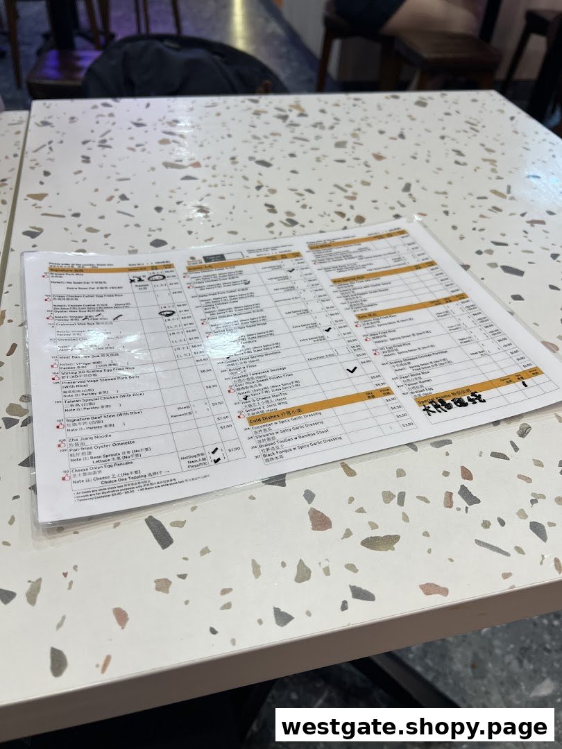 A laminated menu displaying Taiwanese dishes on a speckled white table.