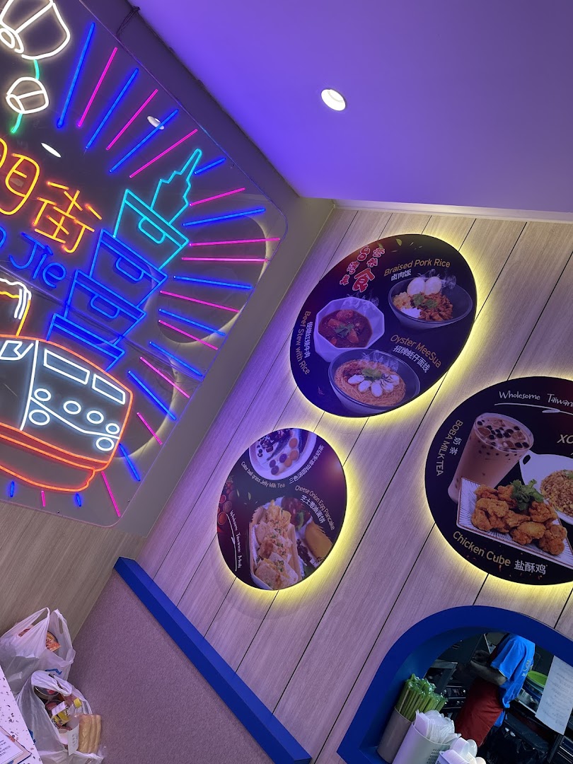 Interior view of Xi Men Jie featuring illuminated posters of Taiwanese dishes and a vibrant neon sign.