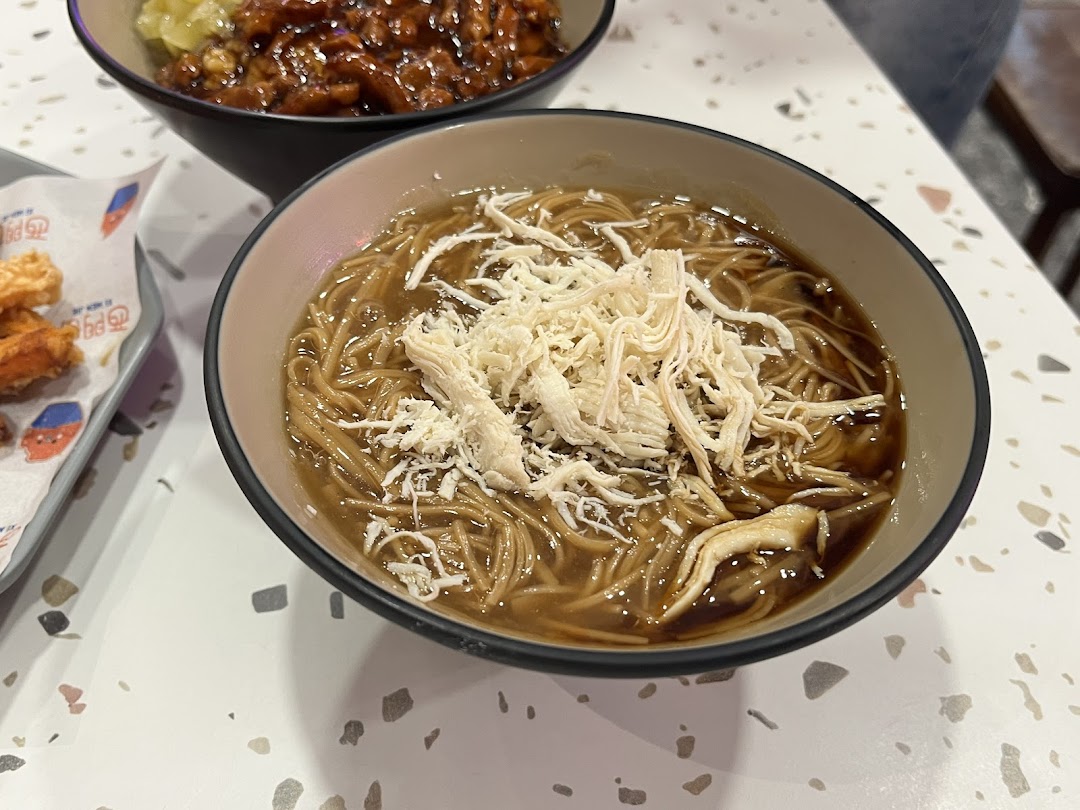 A close-up of a delicious bowl of Taiwanese vermicelli with shredded chicken, served on a speckled white table.
