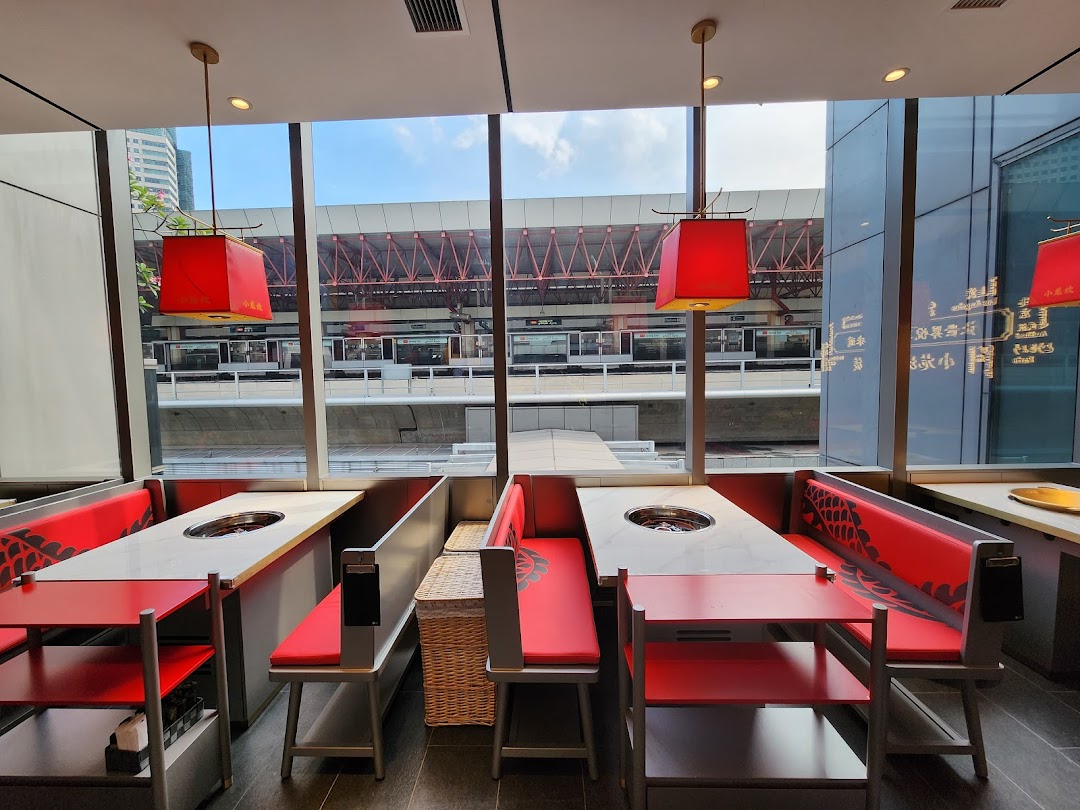 Interior view of Xiao Long Kan Hotpot, featuring modern tables with hotpot inserts and a city view.