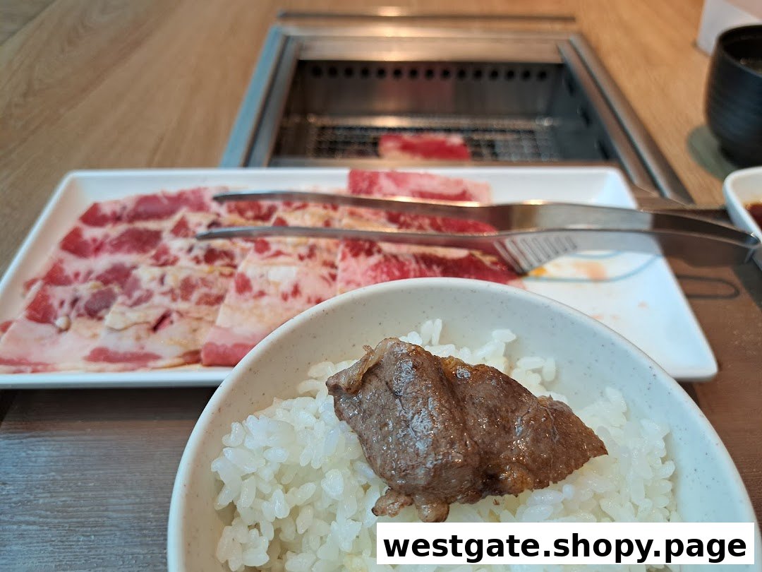 A close-up of a bowl of rice with grilled meat, alongside a plate of raw yakiniku slices and a grill.