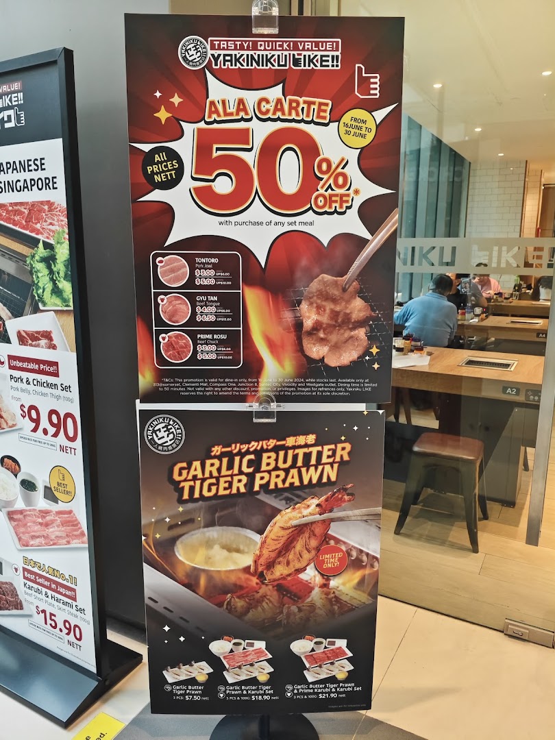 Promotional stands outside Yakiniku Like, showcasing special offers and menu items.