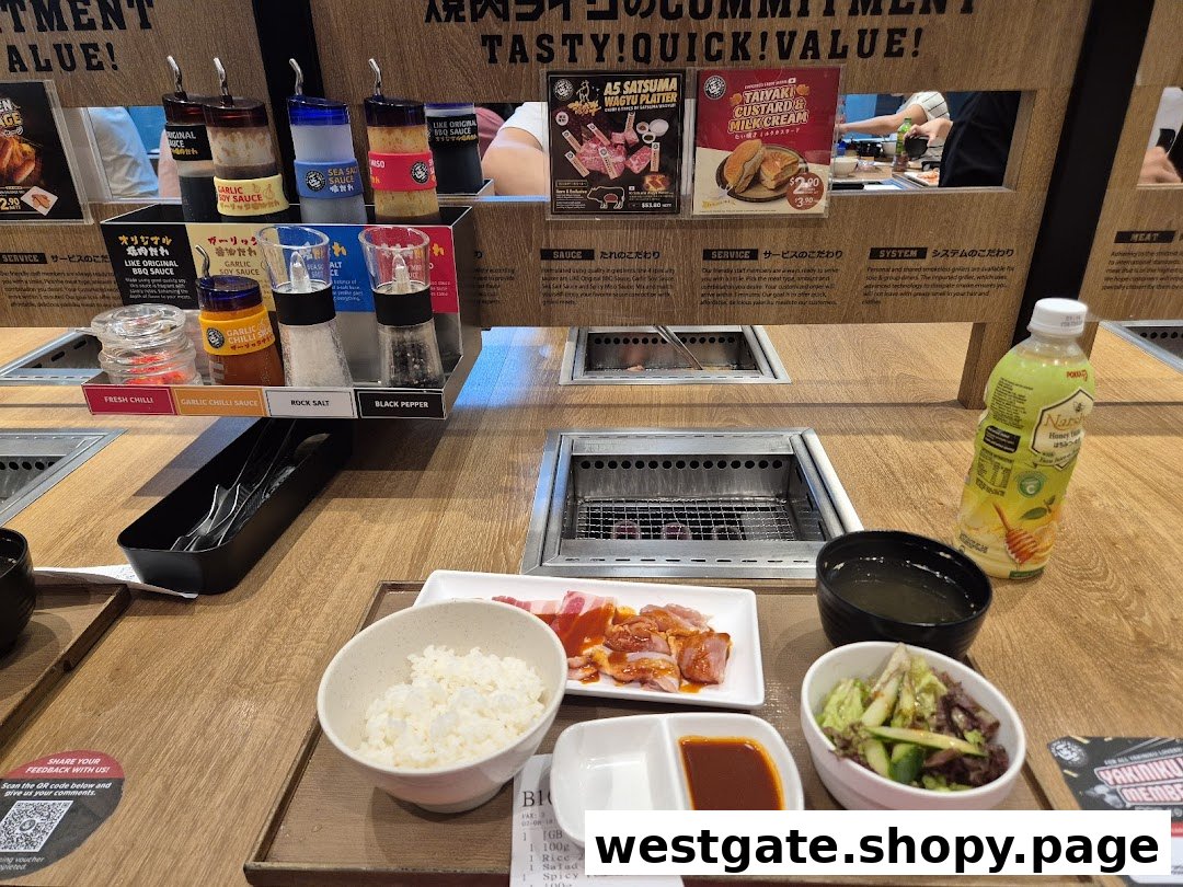 A personal yakiniku grill station with raw meat, rice, salad, sauces, and a drink, ready for grilling.