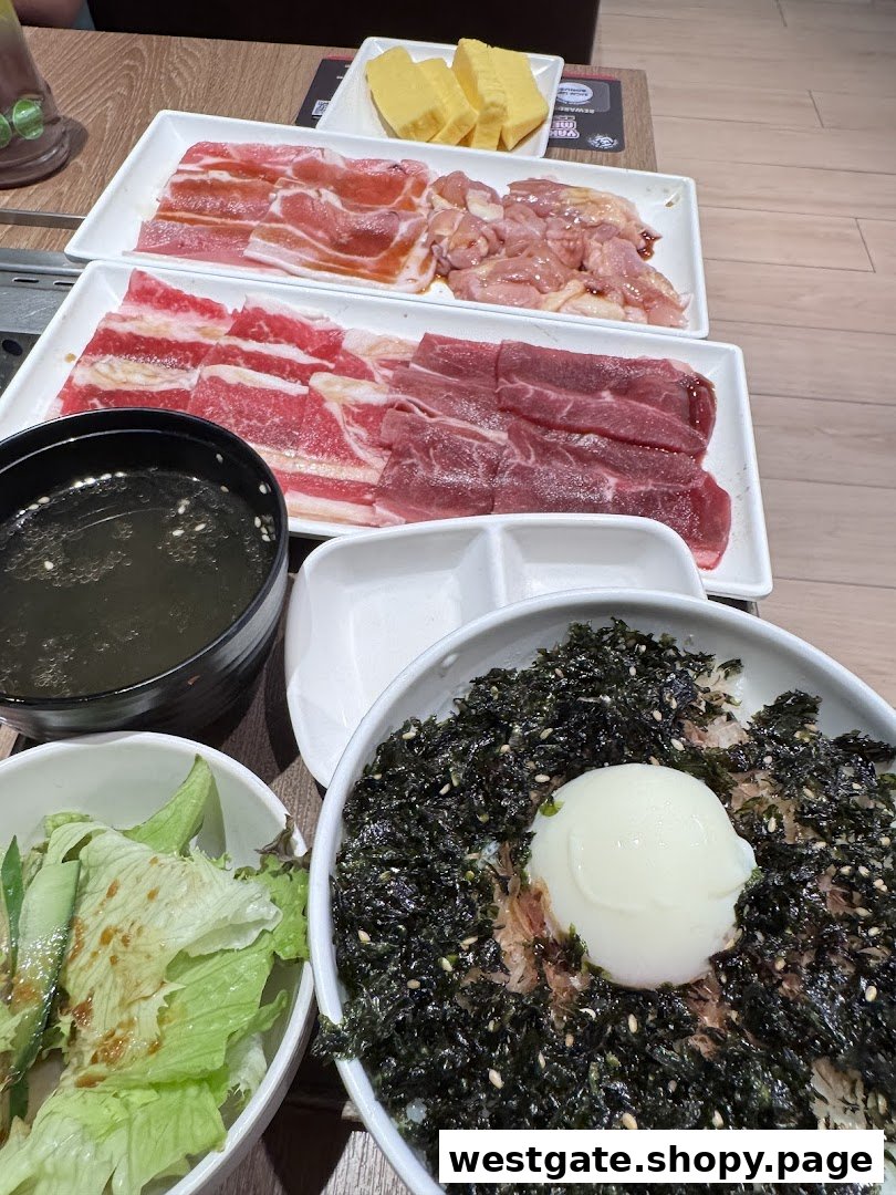 A table laden with raw meats for grilling, a rice bowl, salad, and soup at Yakiniku Like.