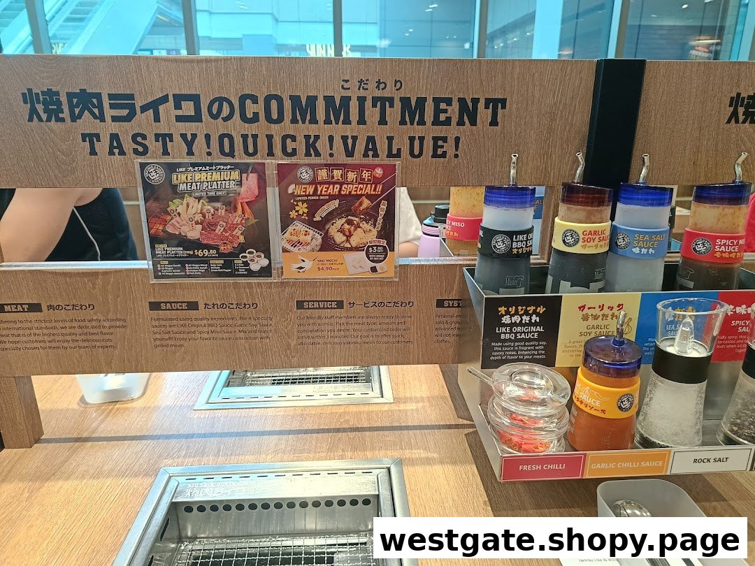 A restaurant table with a built-in grill, various sauces, and promotional posters for meat platters and specials.