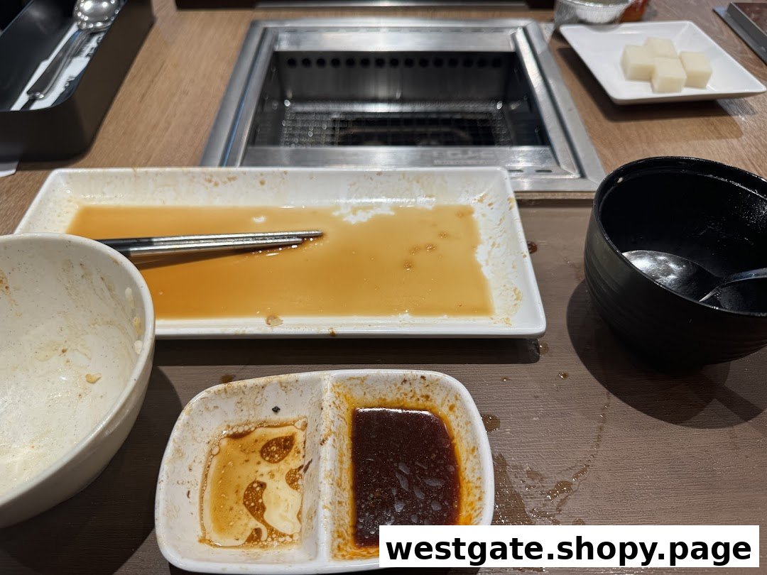 A table at Yakiniku Like with used dishes, sauces, and a grill after a satisfying meal.