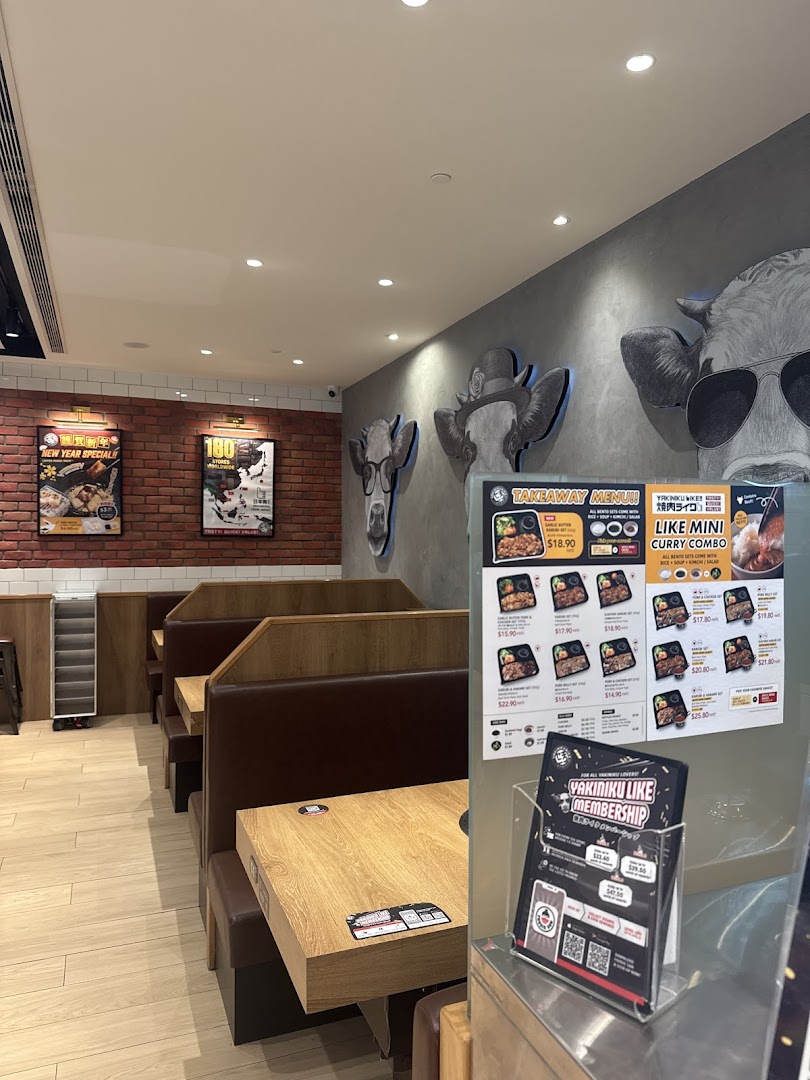 An inviting interior view of Yakiniku Like Westgate, featuring booth seating and unique cow-themed wall art.