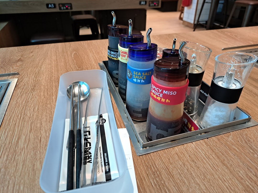 A table setting at Yakiniku Like, featuring various sauces, salt, pepper, and cutlery.