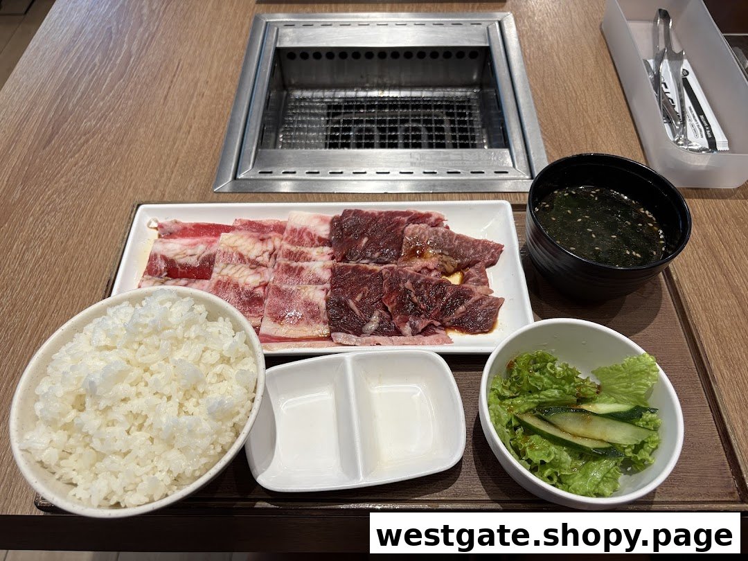 A delicious Yakiniku meal set with raw beef, rice, soup, and salad on a table with a grill.