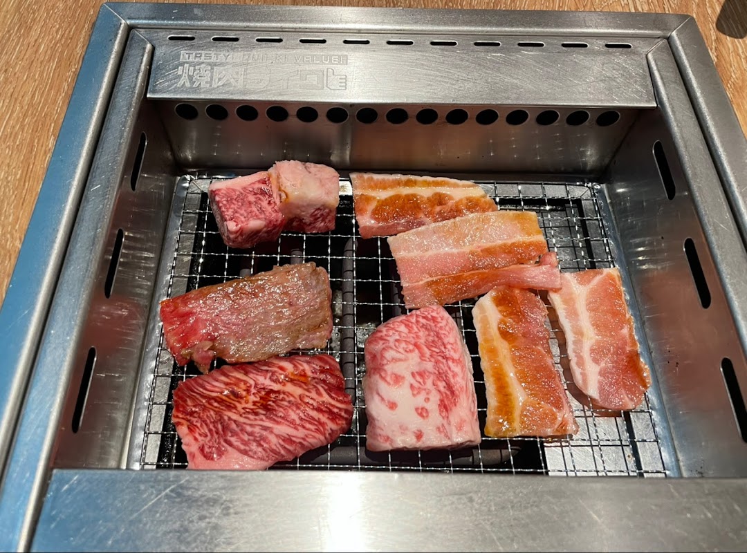 Assorted cuts of fresh yakiniku meat grilling on a personal tabletop grill.
