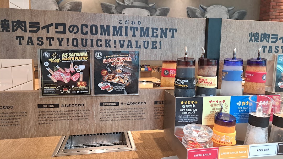 An interior view of Yakiniku Like, showcasing their sauce bar and promotional posters for wagyu and asari.