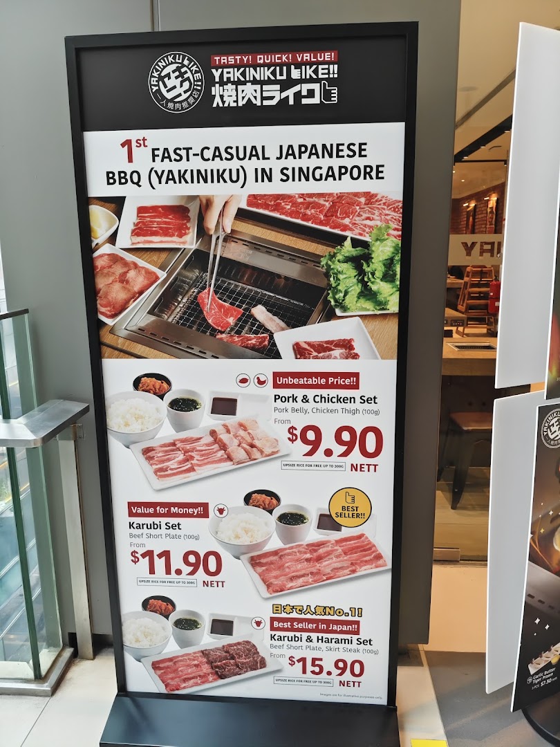 A promotional stand for Yakiniku Like, showcasing their fast-casual BBQ concept and popular sets.
