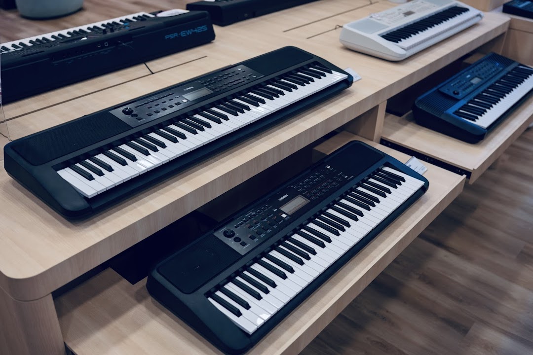 Multiple Yamaha keyboards and digital pianos displayed on wooden shelves in a music store.