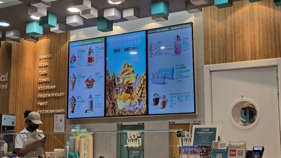 Interior view of Yolé Westgate, featuring digital menu boards, a service counter, and a staff member.
