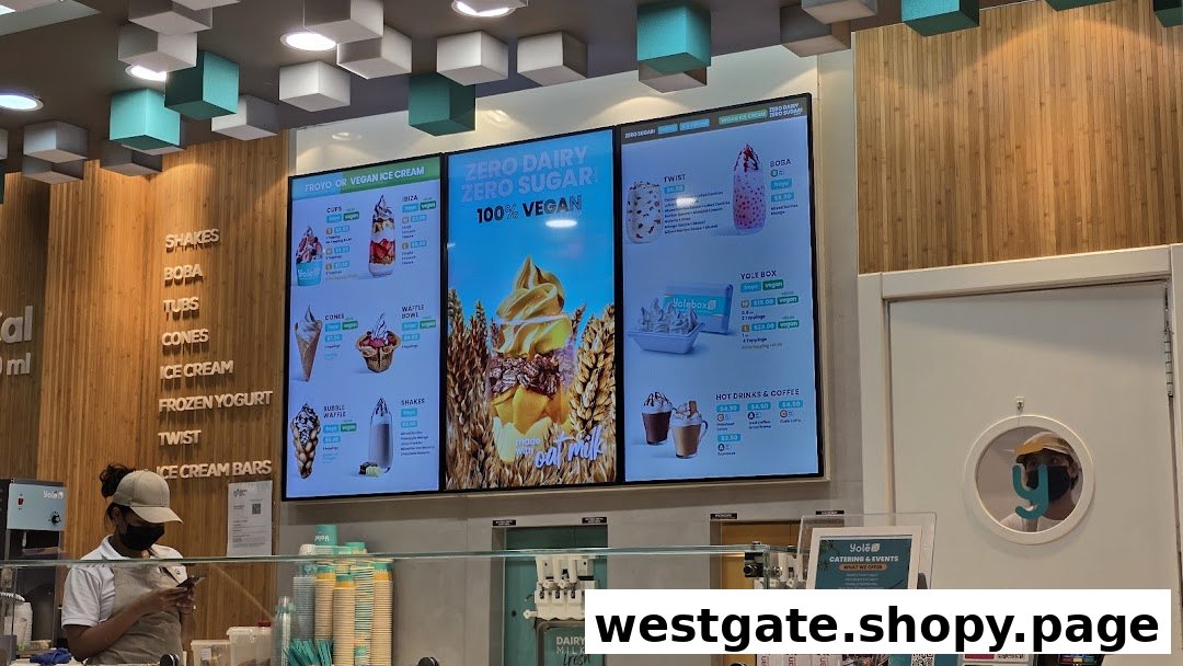 Interior view of Yolé Westgate, featuring digital menu boards, a service counter, and a staff member.