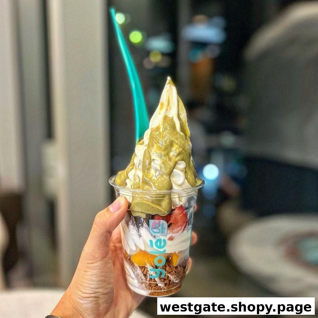 A hand holds a delicious cup of Yolé frozen yogurt with pistachio sauce and fruit toppings.