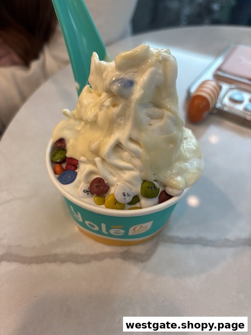 A close-up of a Yolé frozen yogurt cup topped with colorful candies and white chocolate sauce.