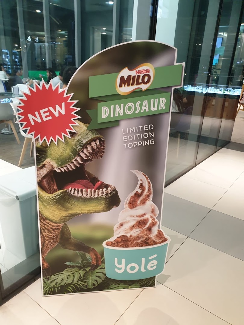 A promotional standee for Yolé's new Nestle Milo Dinosaur limited edition topping with a dinosaur graphic.