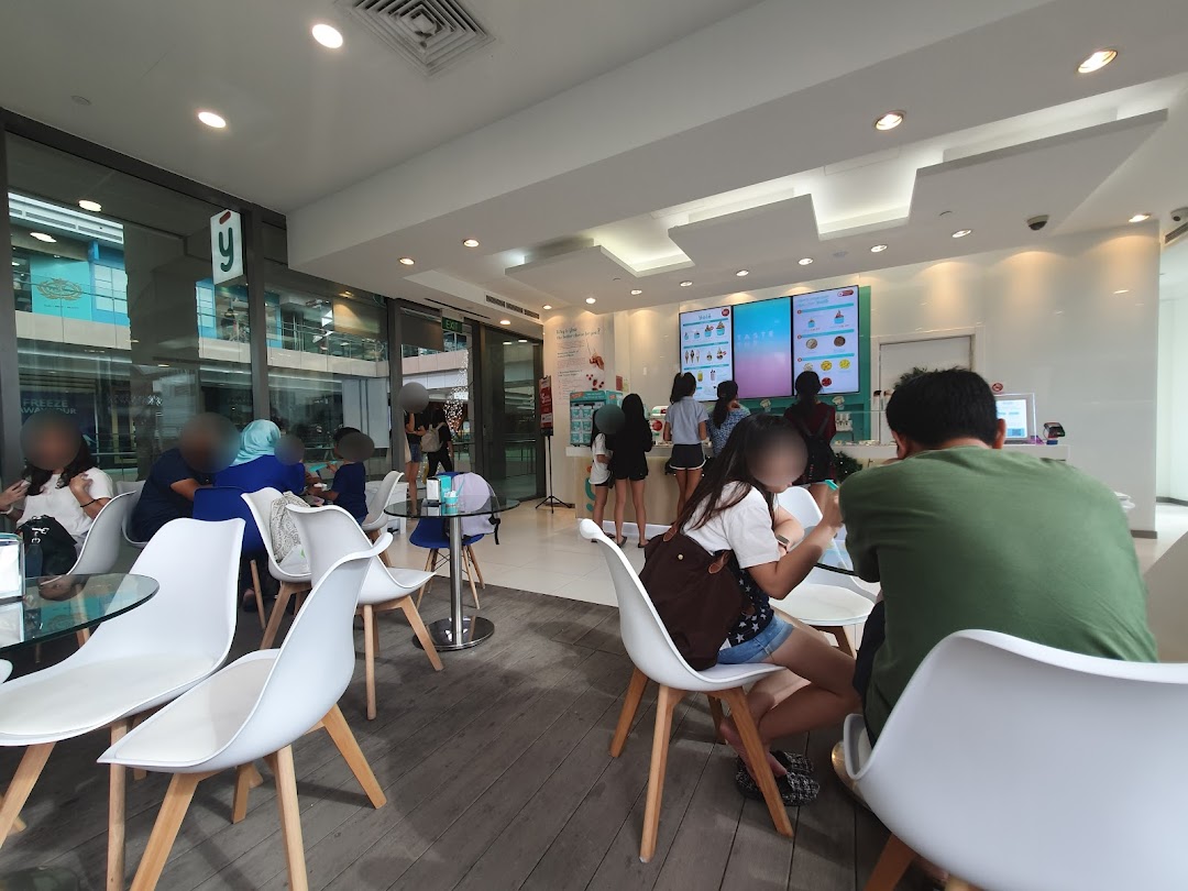 Customers enjoying frozen yogurt in the bright, modern interior of Yolé Westgate, featuring digital menu screens.