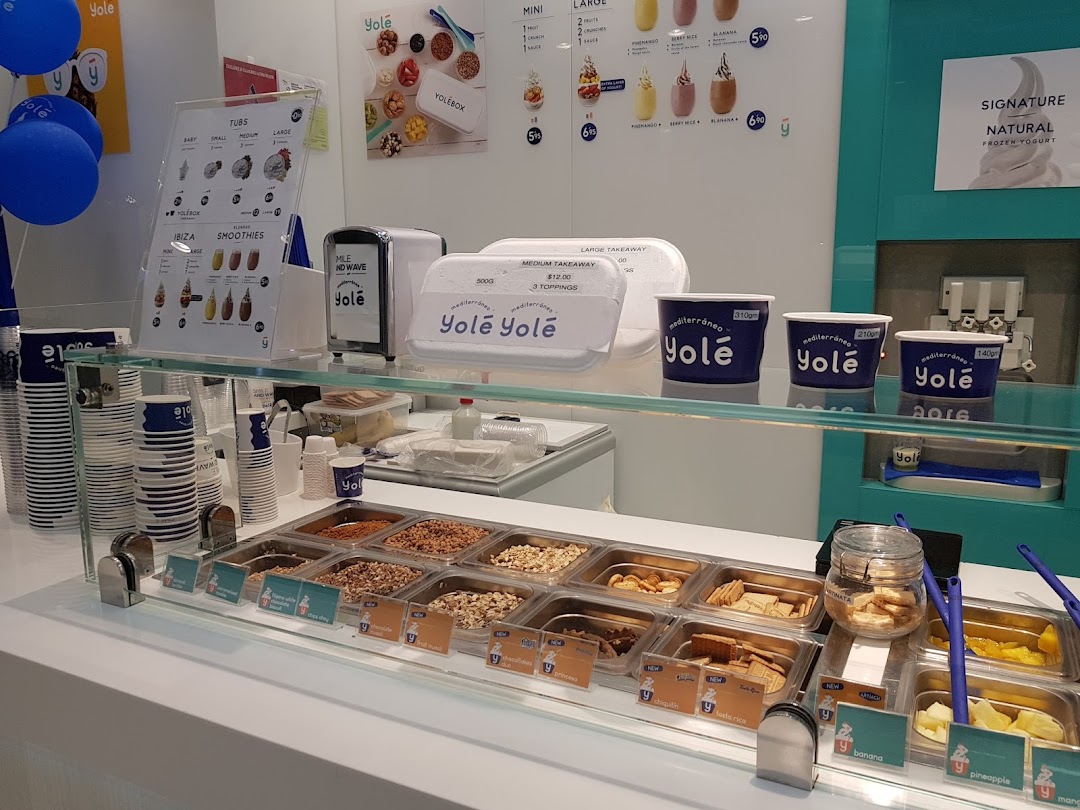 Interior view of Yolé frozen yogurt counter showcasing toppings, cups, and menu displays.