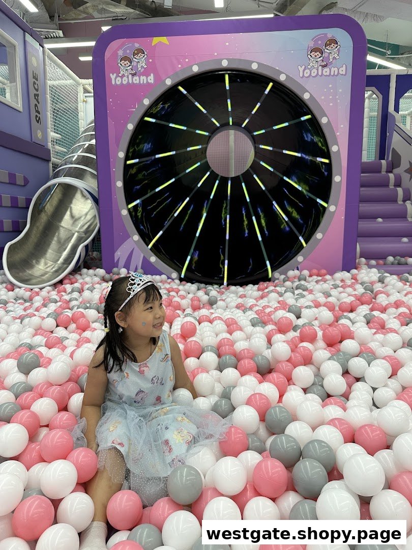 A happy child plays in a vibrant ball pit at Yooland, an exciting indoor playground with space-themed elements.