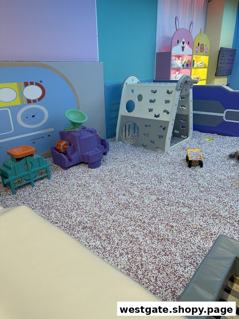 A vibrant indoor play area featuring a large pit filled with small particles and various colorful play structures.
