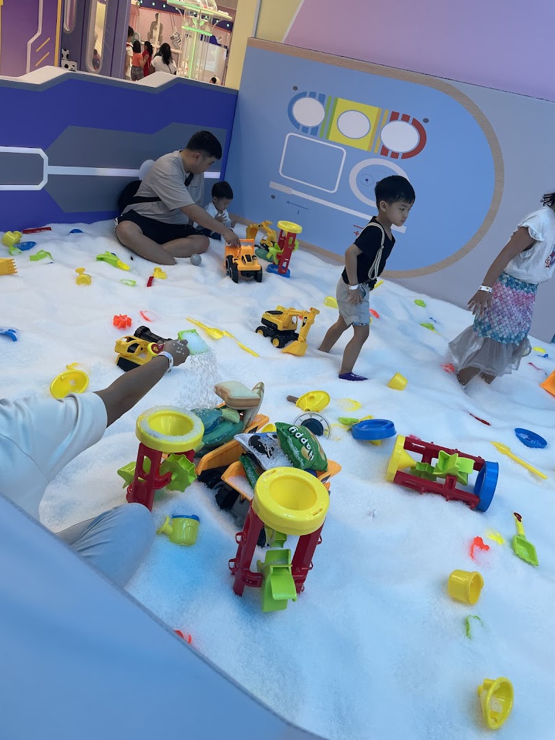 Children and adults play with toys in a white indoor play area at Yooland.