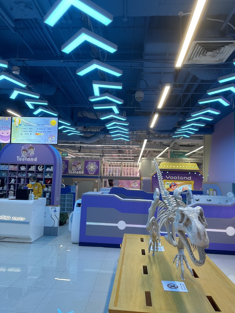 A vibrant Yooland interior featuring a dinosaur display and a visible price list for admission and play passes.