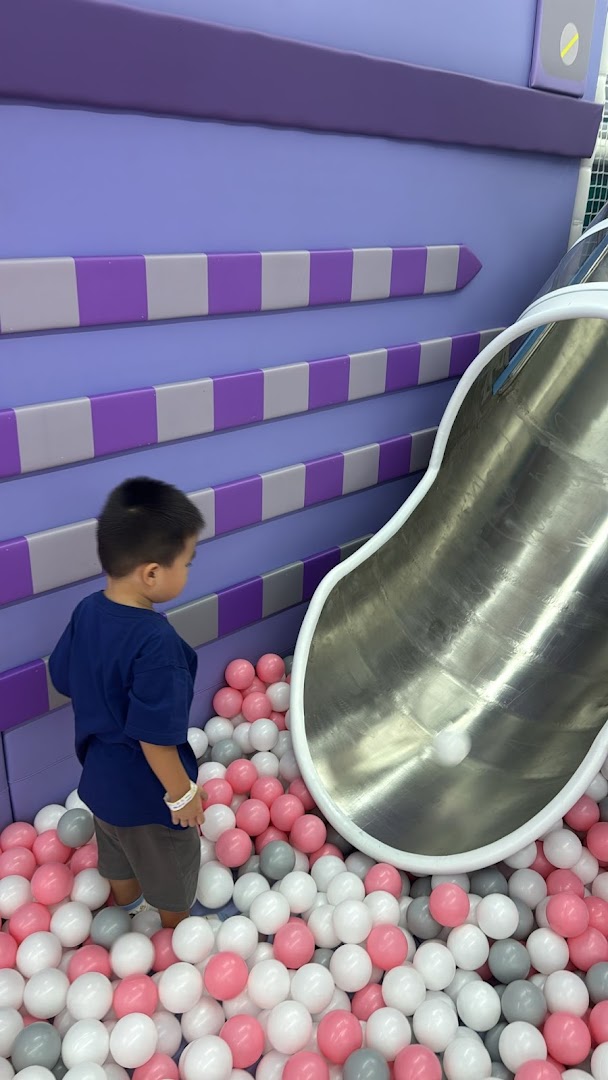 A child plays in a vibrant ball pit with a slide at Yooland.