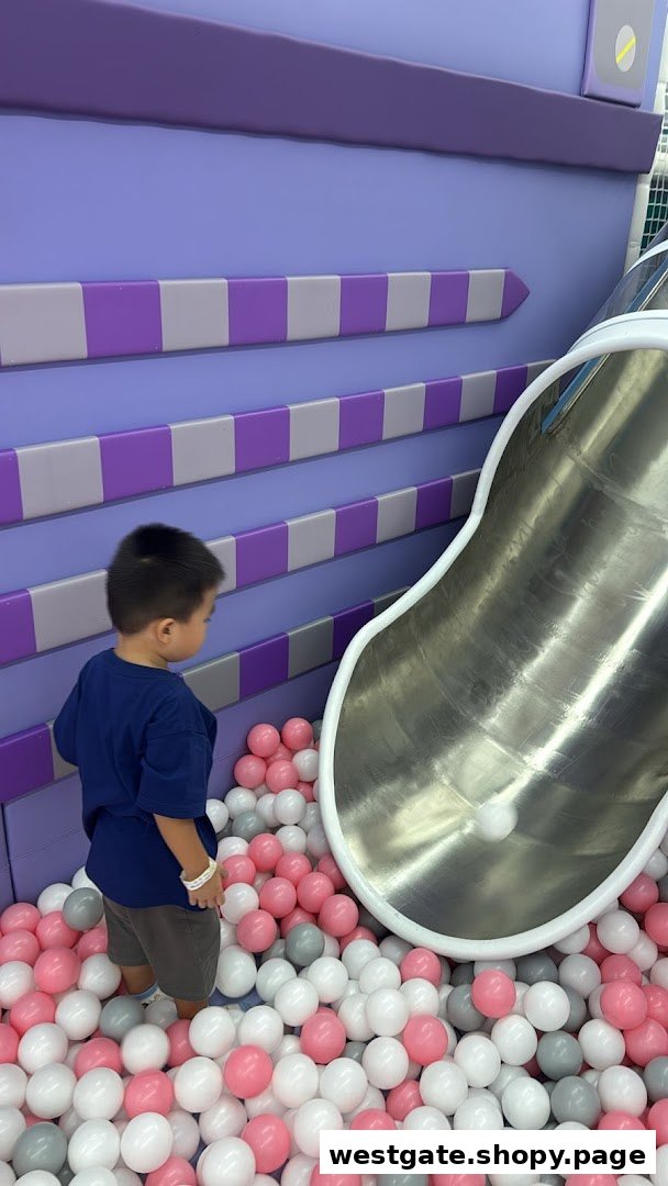 A child plays in a vibrant ball pit with a slide at Yooland.
