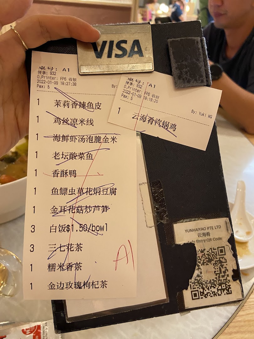 A hand holds a restaurant bill displaying ordered food and drink items.