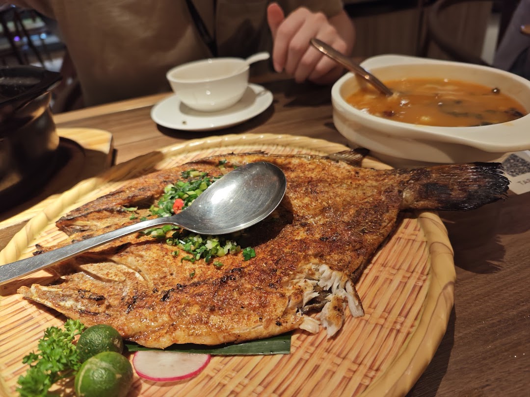 A delicious grilled fish dish with herbs and limes, served alongside a bowl of soup.